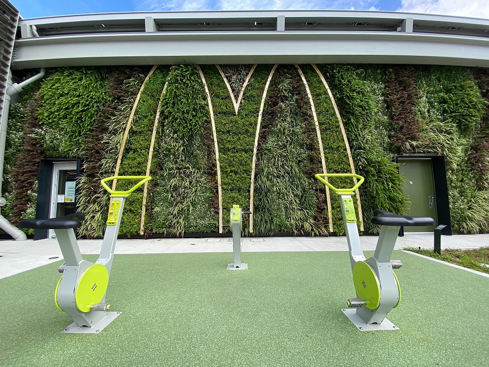 De groene gevel met elektriciteitsopwekkende fietsen waarmee klanten de gele boog kunnen verlichten. De groene gevel met elektriciteitsopwekkende fietsen waarmee bezoekers de gele M kunnen laten oplichten.